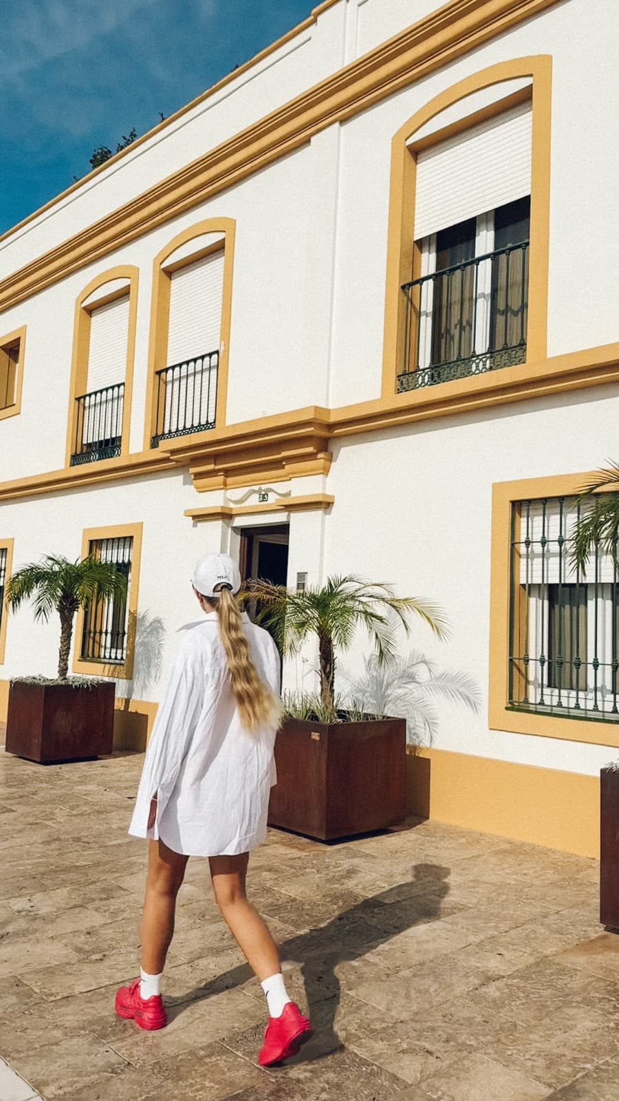 Person i vit skjorta går genom en solbelyst innergård i Marbella