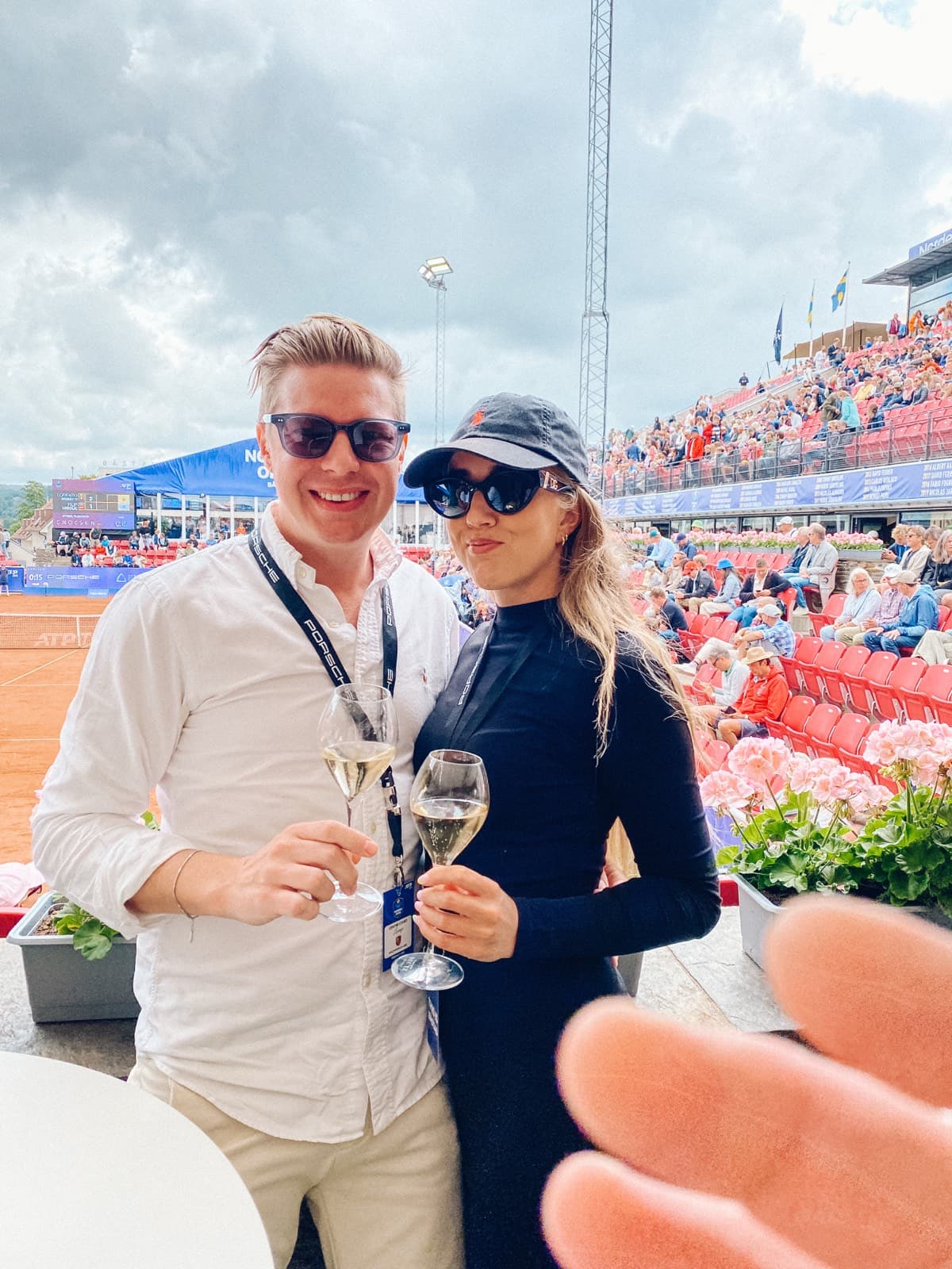Christopher och Marie skålar med champagne på en tennisläktare