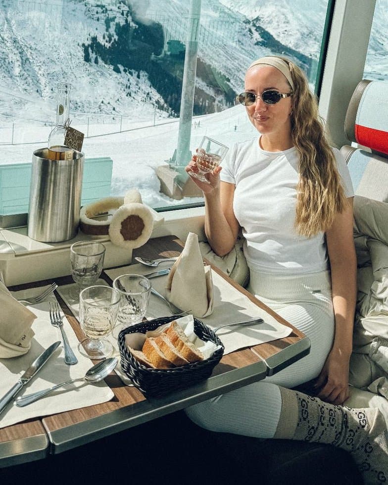 Marie with a glass of wine on a train through the Swiss Alps